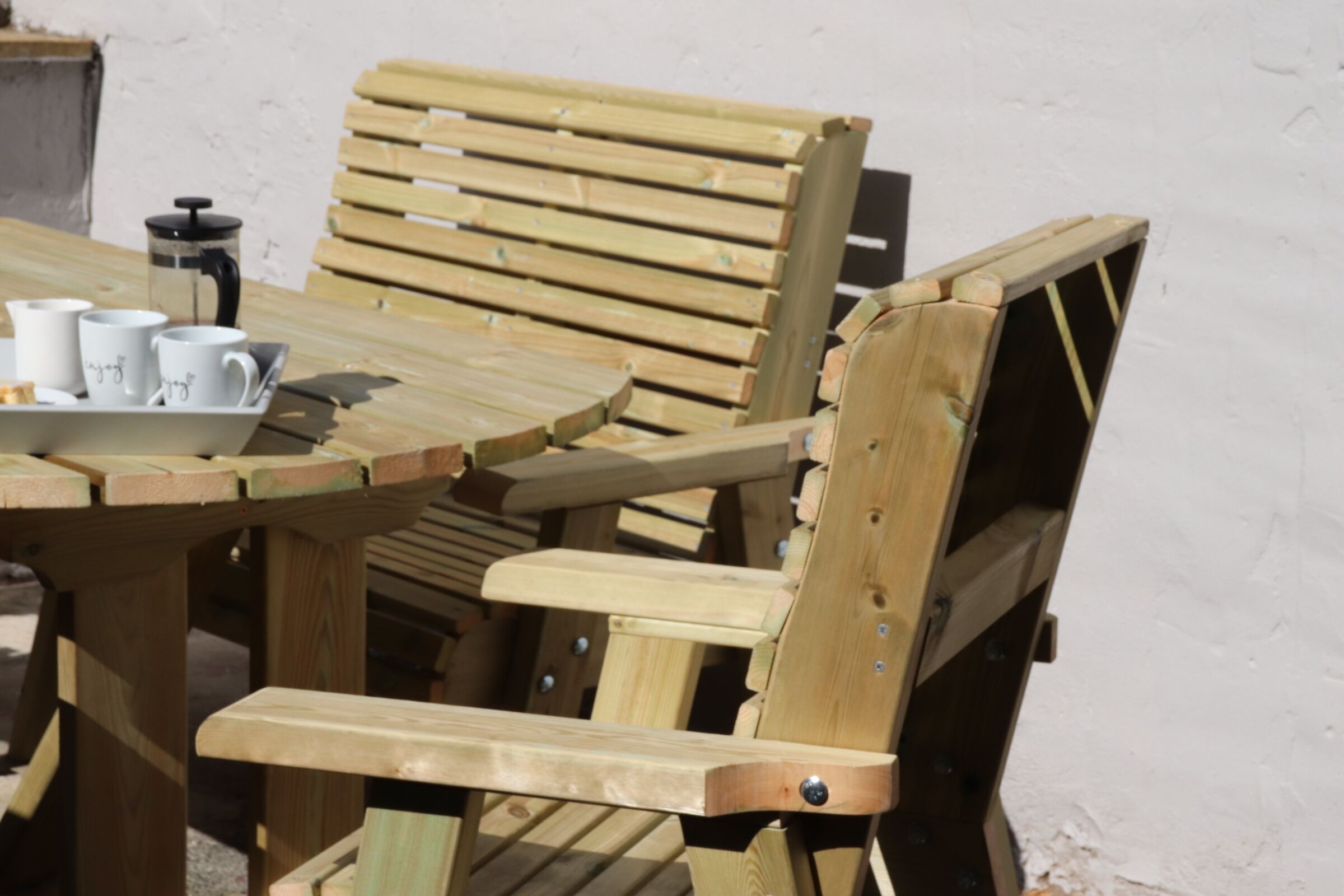 Une table en bois sur laquelle se trouve un plateau avec des tasses blanches et une cafetière.