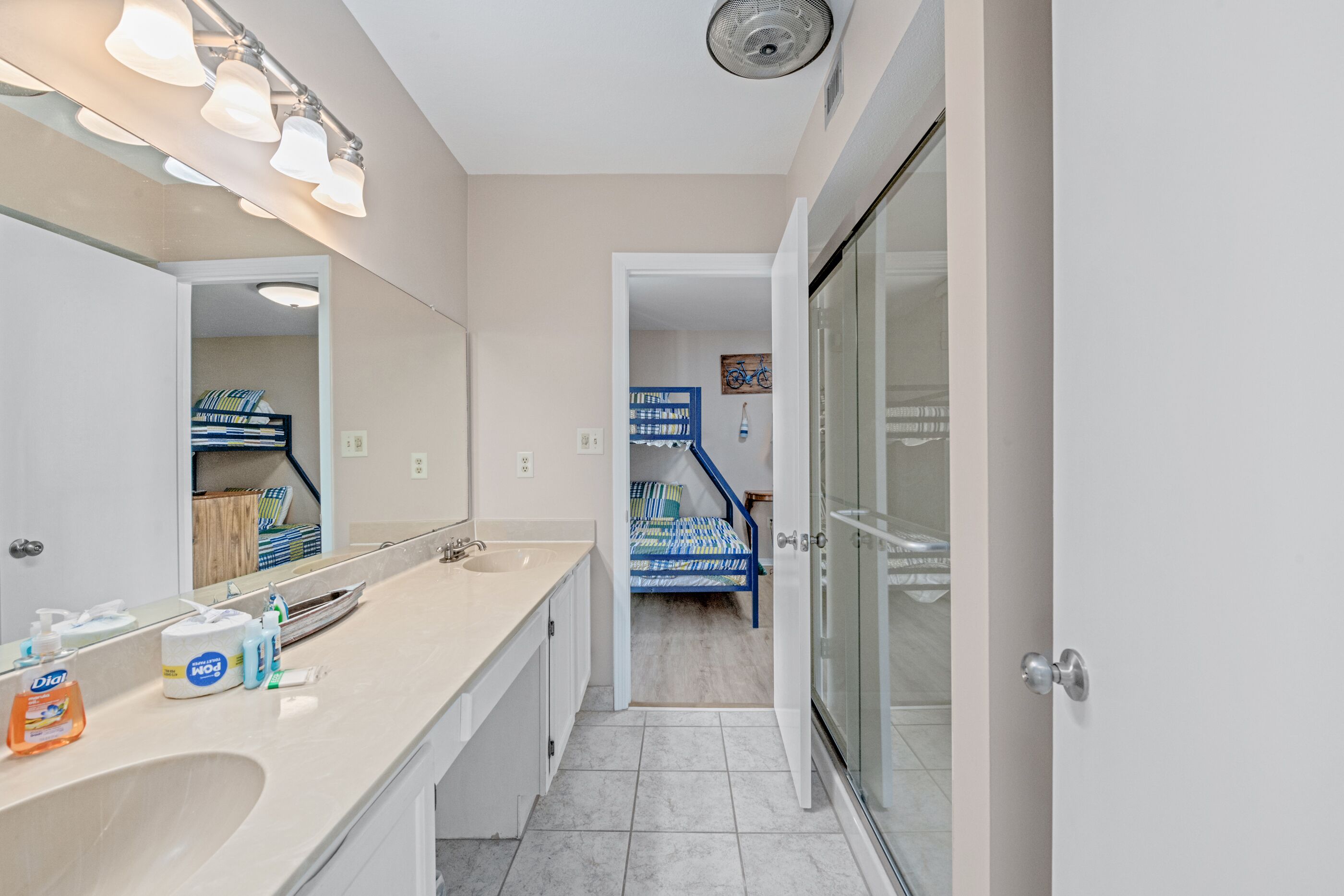A modern bathroom with a large mirror, a sink, and a shower area.