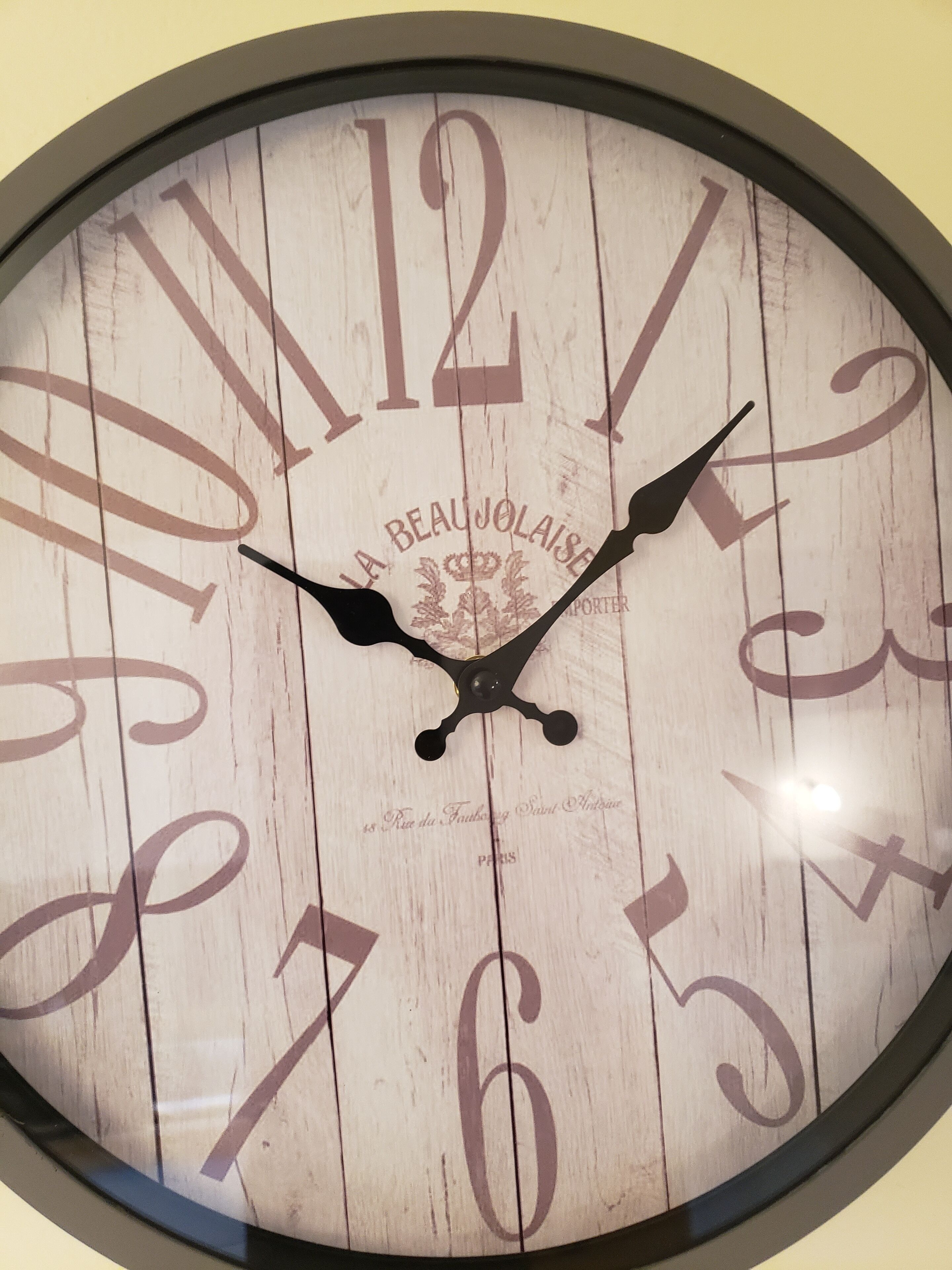A round wall clock with a wooden face and Roman numerals.