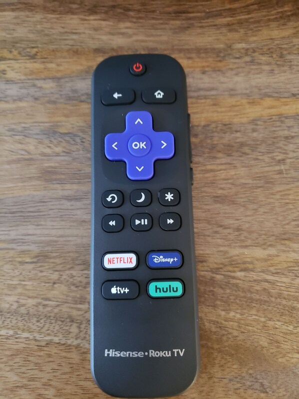 A remote control with directional buttons, a power button, and buttons for Netflix, Disney+, Apple TV+, Hulu, and Roku TV.