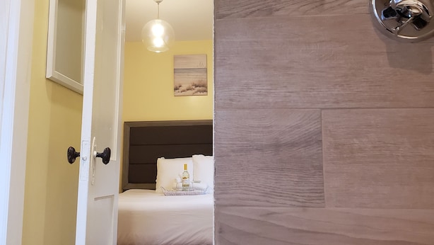 Una habitación de hotel con cama, mesita de noche y un cuadro en la pared.