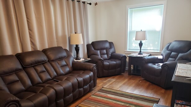 A living room with a brown leather sofa, two armchairs, a small table with a lamp, and a striped rug. - Conveniently located 2 bedroom home only minutes from hiking and state park fun! (Warren)