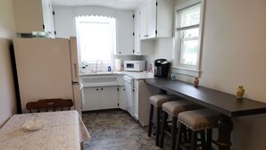 A compact kitchen with white cabinets, a microwave, a coffee maker, and a window with blinds. - Conveniently located 2 bedroom home only minutes from hiking and state park fun! (Warren)