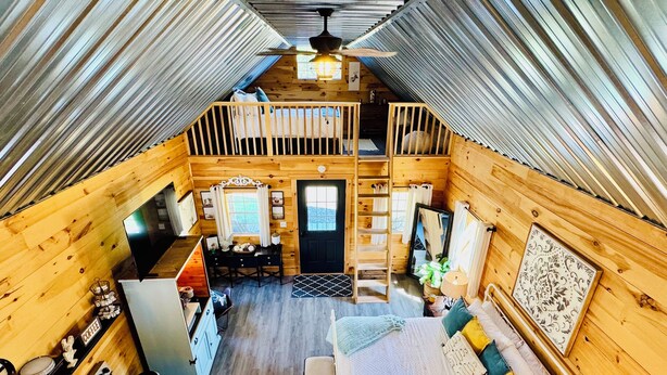 A cozy cabin with a loft bedroom, a dining area, and a kitchen.