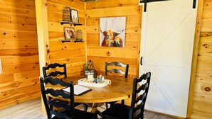A wooden interior with a round table, four chairs, a white door, and wooden walls.