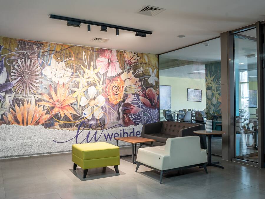 Ein modernes Interieur mit floraler Wandmalerei, einer Sitzecke und einer Glastür zu einem weiteren Raum.