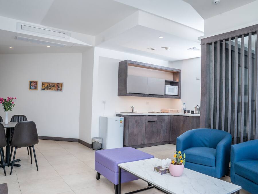 Un espace de vie moderne comprenant une table à manger, des chaises, un pouf violet et des fauteuils bleus.