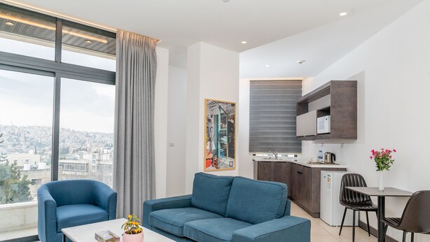 A modern living room with a sofa, a coffee table, and a dining area with chairs. - Liv weibdeh (Amman)