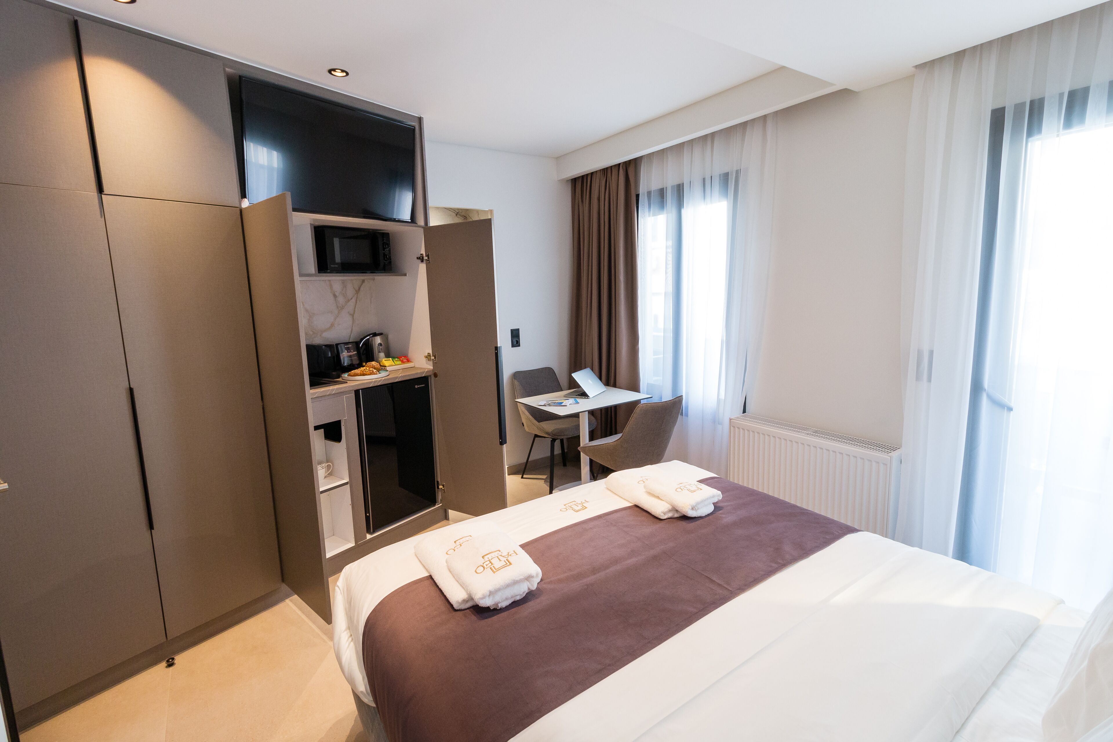 A hotel room with a bed, a desk, a chair, a microwave, and a wardrobe.