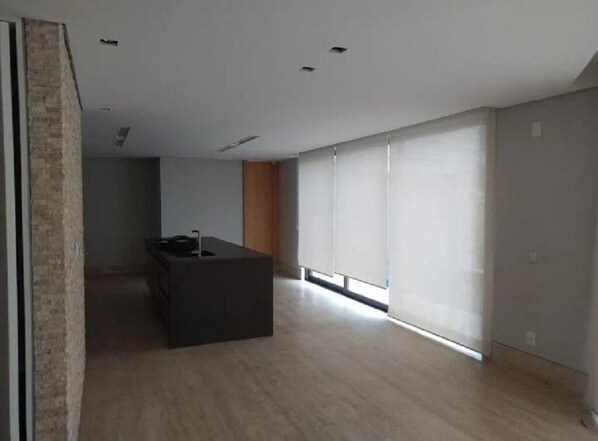 A modern, minimalist room with a large window, a dark-toned central table, and a wooden accent wall.