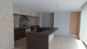 Een moderne keuken met een centraal eiland, inbouwapparatuur en een groot raam.