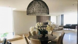 Een eetgedeelte met een ronde tafel, stoelen en een decoratieve hanglamp.