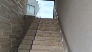 Een trap met een modern ontwerp, van steen of beton, die naar een hoger gelegen niveau leidt.