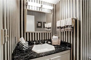 Bathroom features a white sink with a countertop, a towel rack, and a framed picture on the wall.