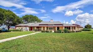 A two-story house with a brick exterior, a red roof, and a well-maintained lawn.