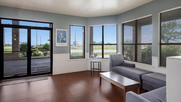 A spacious living room with a large sliding glass door, a ceiling fan, and a view of the outdoors.