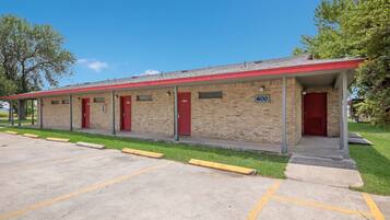 A motel with a brick facade, red doors, and a parking lot with yellow lines.