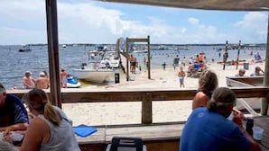 A beachside restaurant with outdoor seating overlooking the water. - Quaint Cottage by the Bay - Boat Launch 1 Street Over (Elberta)