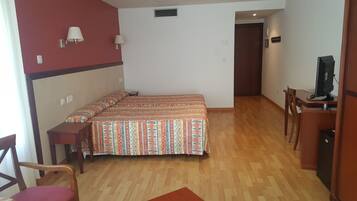 Un dormitorio con una cama doble, un escritorio con computadora y una silla.