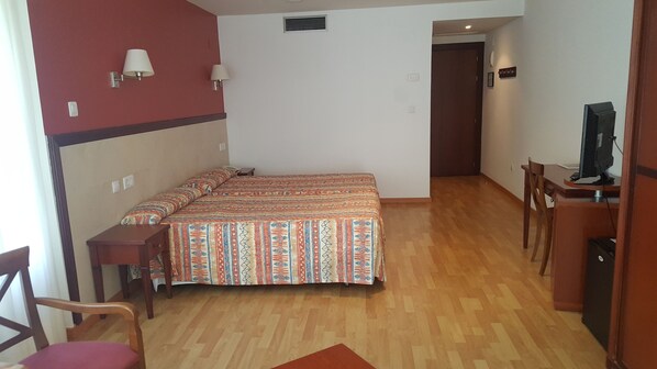A bedroom with a double bed, a desk with a computer, and a chair.