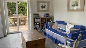 Una sala de estar con un sofá azul a rayas, un cofre de madera y una estantería.