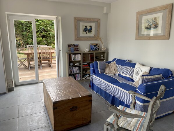 A living room with a blue-striped sofa, a wooden chest, and a bookshelf.