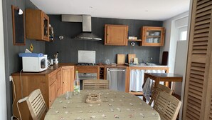 Cocina compacta con armarios de madera, microondas, estufa y lavavajillas.