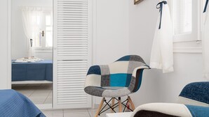 Quarto com cama, cadeira, janela com cortinas e porta com design veneziano.