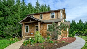A two-story wooden house with a porch, surrounded by a garden with various plants and flowers. - Rancho Relax Inn  (CARLTON)