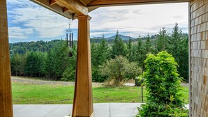 A covered porch with a view of a forested hillside. - Rancho Relax Inn  (CARLTON)