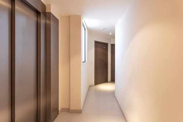 A corridor with a modern elevator and a door at the end.