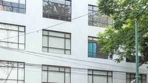 Un bâtiment moderne doté de nombreuses fenêtres, avec un arbre bien visible au premier plan.