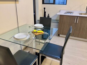 Eine moderne Küche mit einem Glastisch, Stühlen und einer weißen Arbeitsplatte.