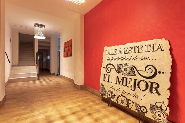 A hallway with a red wall and a sign that reads "DALE A ESTE DIA la posibilidad de ser... EL MEJOR dia de tu vida!"