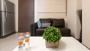 A compact living space with a kitchenette, a brown leather sofa, a white coffee table with a potted plant, and two water bottles. - Comfortable and reliable stay, convenient location (Mexico City)