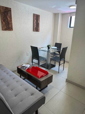 A dining area with a glass table, black chairs, and a red tray on a wooden table.