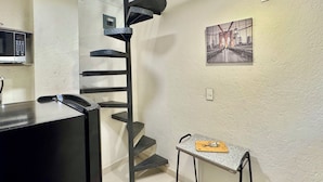 A kitchen with a microwave, a black refrigerator, a staircase, a small table with a keychain, and a framed picture on the wall. - Reliable Double-Height Stay. Great CDMX Location (Mexico City)