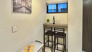 A small kitchen with a dining table, two bar stools, a small window, and a painting on the wall. - Reliable Double-Height Stay. Great CDMX Location (Mexico City)