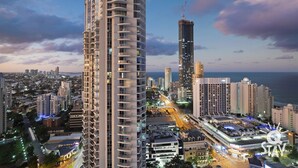 A high-rise hotel with a modern design, featuring multiple balconies and a prominent view of the city skyline. - 3 Bed Executive Sub Penthouse with Ocean Views (Surfers Paradise)