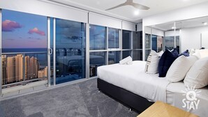 A modern bedroom with a large bed, a city view, and a ceiling fan. - 3 Bed Executive Sub Penthouse with Ocean Views (Surfers Paradise)