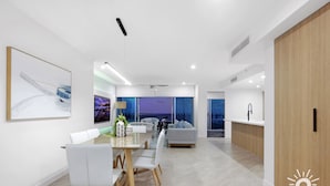 A modern living room with a dining area, a sofa, and a kitchen. - 3 Bed Executive Sub Penthouse with Ocean Views (Surfers Paradise)