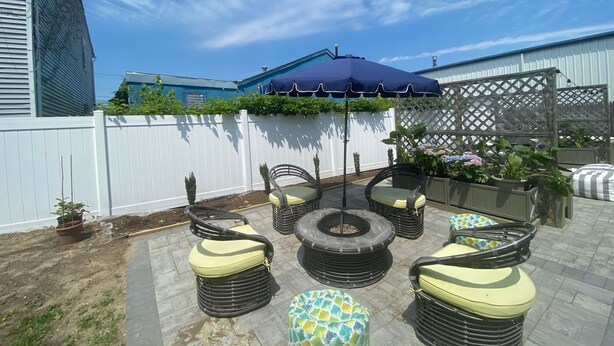 An outdoor patio with wicker furniture, a blue umbrella, and potted plants. - Charming 4bedroom 2nd Floor Beach House - 1.5 blocks to the beach (Long Branch)