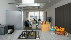 Une cuisine moderne équipée d’une cuisinière à gaz, d’une machine à café et d’un panier à fruits.