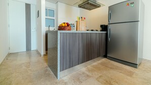 Une cuisine moderne dotée d’un réfrigérateur en acier inoxydable, d’un plan de travail en granit et d’un four encastré.