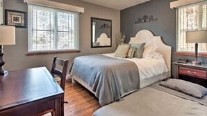 Een slaapkamer met een bed, nachtkastje, lamp en een plafondventilator.