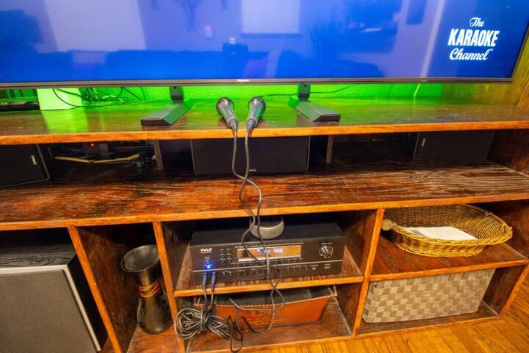 Un meuble de rangement en bois comprenant un téléviseur, du matériel de karaoké et un système audio.