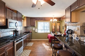 A kitchen with dark wooden cabinets, a stainless steel stove, and a red dining table with chairs.