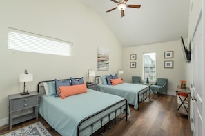 A bedroom with two beds, a nightstand, a chair, a ceiling fan, and a window with blinds.