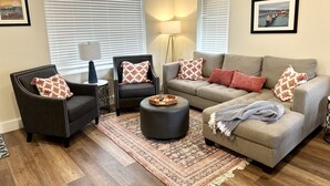 A living room with a grey sofa, two armchairs, a coffee table, and a patterned rug. - New - Lookout Views 2 Br/2BA Sleeps 8 next to OddStory Brewery! Pet friendly! (Chattanooga)