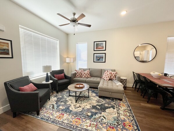 A living room with a sofa, armchairs, a coffee table, and a dining area with a table and chairs.